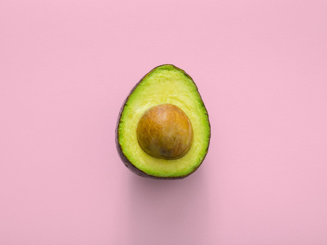 half of an avocado with a pink background